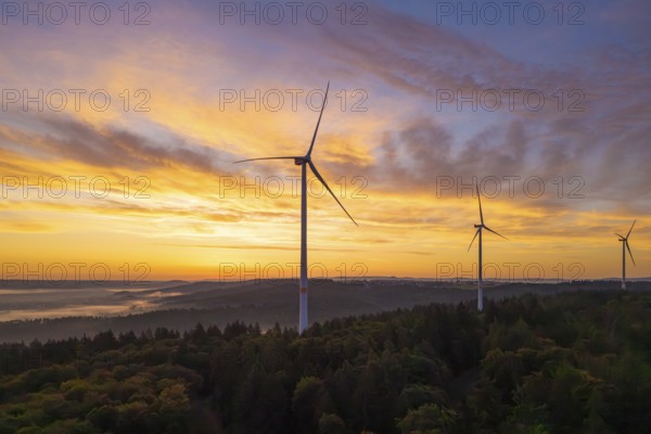 Wind turbines on a hill, dramatic sky colours at sunrise over a forest landscape, near Schorndorf, Remstal, Rems-Murr-Kreis, Baden-Württemberg, Germany