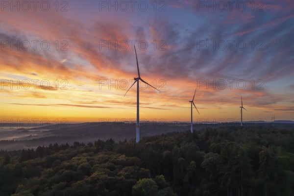Three wind turbines in the foreground of a colourful morning sky over a hilly landscape, near Schorndorf, Remstal, Rems-Murr-Kreis, Baden-Württemberg, Germany