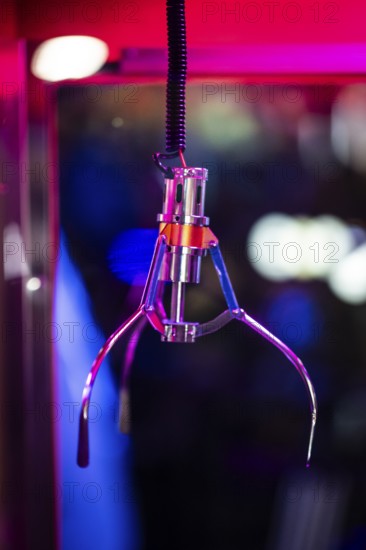 A shiny gripping arm of a vending machine, combination of vending machine and slot machine under neon-coloured light in a futuristic atmosphere, Soho, London, England, United Kingdom