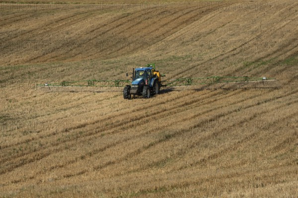 Tractor spreading fertilizer on harvested stubble field in Ystad municipality, Skåne county, Sweden, Scandinavia
