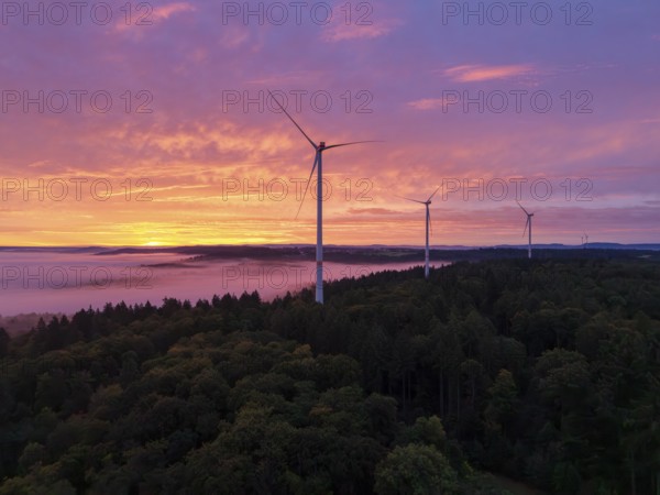 Several wind turbines above a forest in front of sunrise in the warm colours of dusk, near Schorndorf, Rems-Murr district, Rems-Murr-Kreis, Baden-Württemberg, Germany