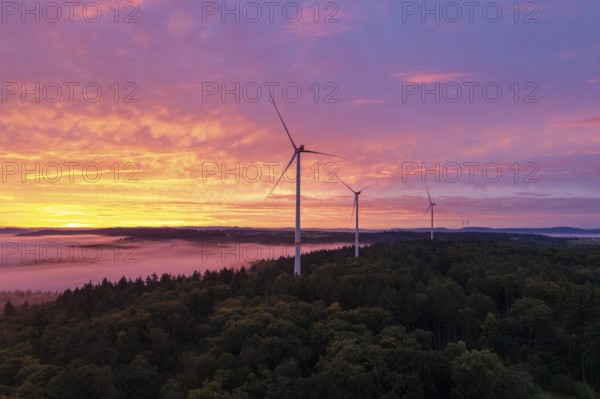 Three wind turbines above a forest in front of sunrise in a vivid colour mood, near Schorndorf, Rems-Murr district, Rems-Murr-Kreis, Baden-Württemberg, Germany