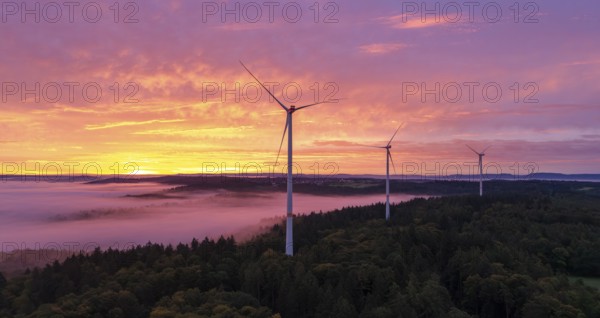 Wind turbines above a forest in front of sunrise with dramatic cloud formation, near Schorndorf, Remstal, Rems-Murr-Kreis, Baden-Württemberg, Germany
