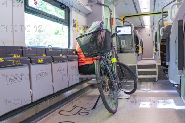 A cyclist sits in a modern, bright train compartment with his bicycle, battery Electric train with green electricity, Siemens Mireo Plus B, Freudenstadt, Germany
