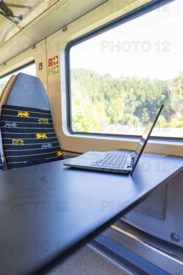 Laptop on a folding table in front of a window with a view in a vehicle, battery Electric train with green electricity, Siemens Mireo Plus B, Freudenstadt, Germany
