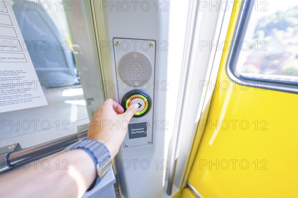 Hand presses stop button on a yellow door in the interior, battery Electric train with green electricity, Siemens Mireo Plus B, Freudenstadt, Germany