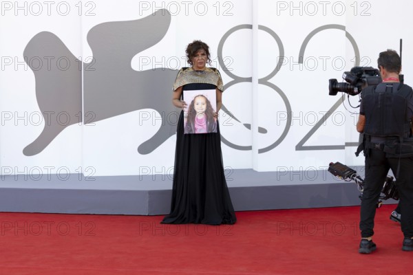 Venice, Italy - 3 September 2025: Kaouther Ben Hania with a portrait of five-year-old Palestinian girl Hind Rajab, who was killed by the Israeli army in the Gaza Strip in January 2024, during the red carpet of - The Voice Of Hind Rajab - during the 82nd Venice International Film Festival