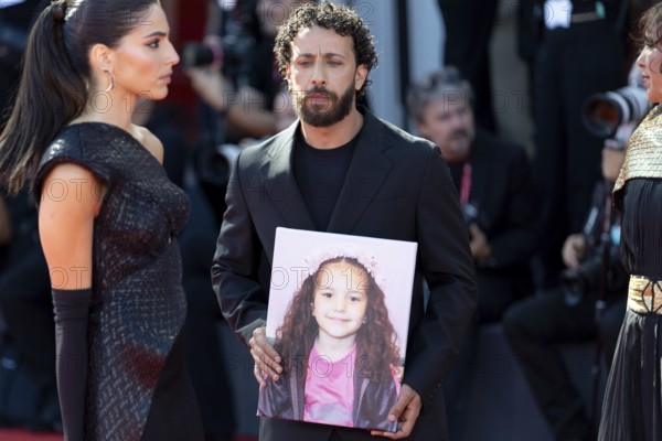 Venice, Italy - 3 September 2025: Kaouther Ben Hania (R) and Saja Kilani (L) and Motaz Malhees (C) with a portrait of five-year-old Palestinian girl Hind Rajab, who was killed by the Israeli army in the Gaza Strip in January 2024, during the Red Carpet of - The Voice Of Hind Rajab - during the 82nd Venice International Film Festival