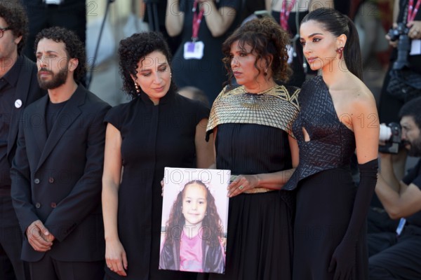 Venice, Italy - 3 September 2025: Kaouther Ben Hania (2vR) and Saja Kilani (R) with a portrait of five-year-old Palestinian girl Hind Rajab, who was killed by the Israeli army in the Gaza Strip in January 2024, during the red carpet of - The Voice Of Hind Rajab - during the 82nd Venice International Film Festival
