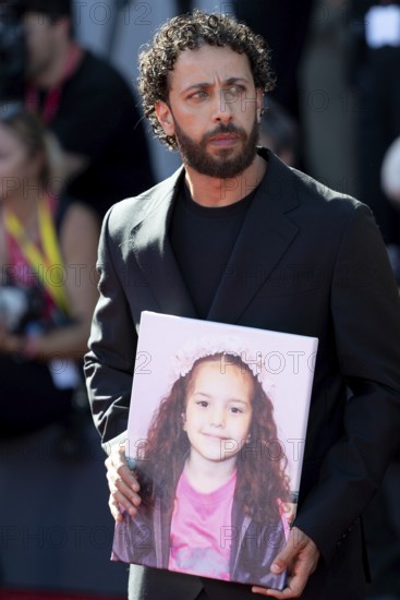 Venice, Italy - 3 September 2025: Motaz Malhees with a portrait of five-year-old Palestinian girl Hind Rajab, who was killed by the Israeli army in the Gaza Strip in January 2024, during the red carpet of - The Voice Of Hind Rajab - during the 82nd Venice International Film Festival