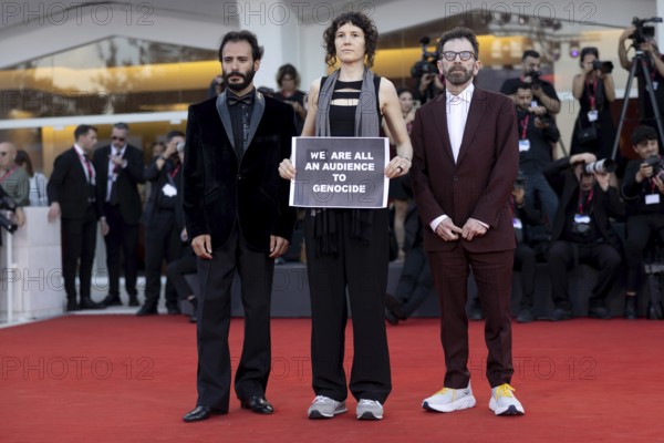 Venice, Italy - 1 September 2025: Charlie Kaufman, Eva H.D. and Josef Akiki with a sign reading - We are all an audience to Genocide - during the Red Carpet of - The Smashing Machine - during the 82nd Venice International Film Festival