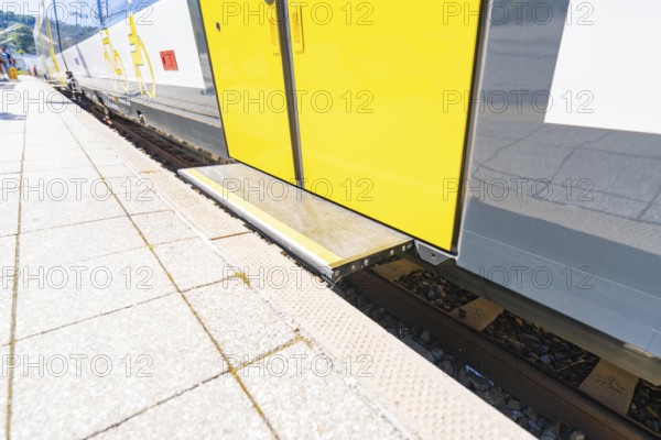 Close-up of the boarding area of a yellow and white train on the track, battery Electric train with green electricity, Siemens Mireo Plus B, Freudenstadt, Germany