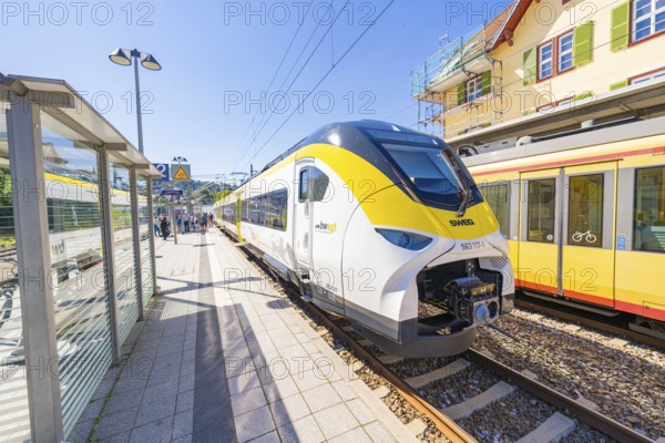 Yellow and white train at a stop, busy railway station under a clear sky, battery Electric train with green electricity, Siemens Mireo Plus B, Freudenstadt, Germany