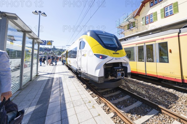 Modern yellow and white train at the station with green and red building in the background, battery Electric train with green electricity, Siemens Mireo Plus B, Freudenstadt, Germany