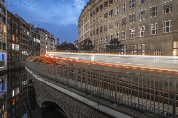 Long exposure at Mönkedamm with underground line U3 and light strip and St Michael's Church in the background at blue hour, Hamburg, Germany
