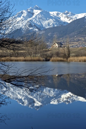 The snow-covered Haut de Cry mountain range is reflected in the Mont d'Orge lake, Lac de Mont d'Orge, Montorge, Sion, Valais, Switzerland