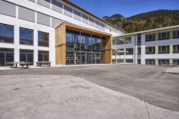 Primary and secondary school Bischofswiesen, primary school, secondary school, building, entrance area, entrance, schoolyard, mountains, coniferous forest, blue sky, town hall square, Bischofswiesen, district Berchtesgadener Land, Bavaria, Germany