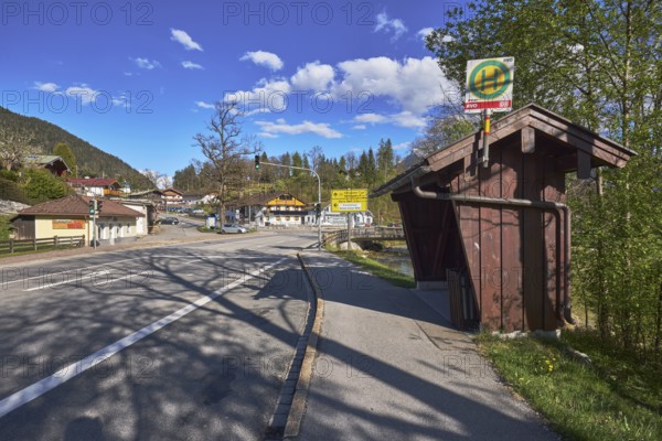 Bus stop, road, traffic lights, trees, hill, coniferous forest, building, shadow, blue sky, cumulus clouds, intersection of federal road 20, main road with Aschauerweiherstraße, Bischofswiesen, district Berchtesgadener Land, Bavaria, Germany