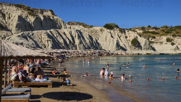 Pleasant scenery on the beach with beach loungers, bathers and magnificent rocky backdrop, Limanaki beach, sandstone rocks, Kolymbia, Rhodes, Dodecanese, Greek Islands, Greece