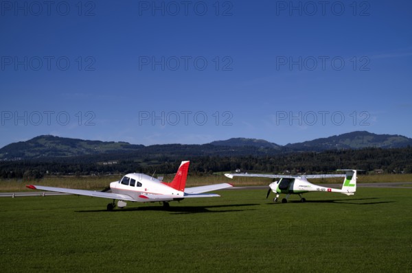 Pipistrel Velis Club on the right with aircraft registration HB-NPP stands next to Piper Archer II HB-PPY on the left on the ground, Wangen-Lachen airfield, LSPV, Canton Schwyz, Switzerland