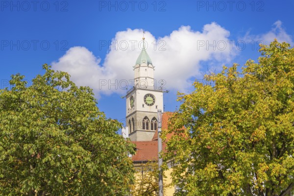 Church tower with red roof and clock above trees under a blue sky, Lake Constance, Germany