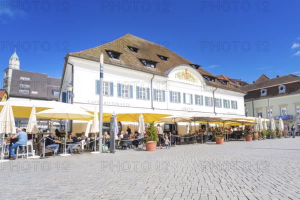 Historic building with a café and yellow parasols in the sunshine, Lake Constance, Germany