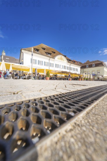 Café with yellow parasols and historic buildings under a clear sky, Lake Constance, Germany