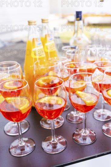 Several cocktail glasses with orange-coloured drink and orange slices, arranged on a table outdoors, Lake Constance, Germany