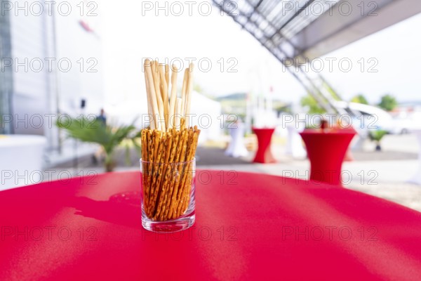 A jar of breadsticks stands on a red table at an outdoor event, Lake Constance, Germany