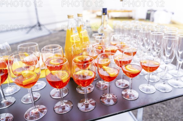 Many cocktail glasses with orange-coloured drink on a table at an outdoor party, Lake Constance, Germany