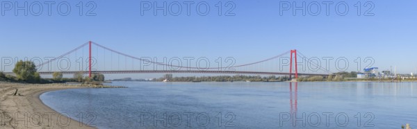 Panorama view from the left bank of the Rhine, western bank of the Rhine, of an earth-anchored suspension bridge with two abutments and red steel piers nicknamed the Golden Gate of the Lower Rhine over the River Rhine, with a total length of 1228 metres the longest suspension bridge in Germany, Emmerich, North Rhine-Westphalia, Germany