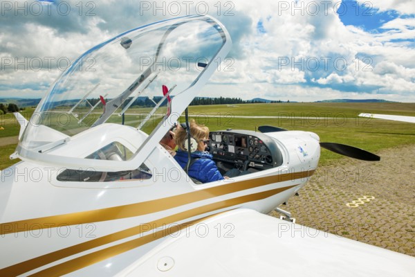 Pilot and passenger co-pilot preparing for take-off in cockpit of two-seater touring motor glider HK36 TC114 Diamond Airplane Super Dimona, two-seater, propeller aircraft, small aircraft, Wasserkuppe airfield, Gersfeld, district of Fulda, Hesse, Germany