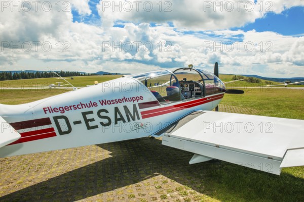 View of Robin Aircraft, DR 400-180R Remo light aircraft single-engine cantilever low-wing monoplane in wooden construction from Fliegerschule Wasserkuppe suitable as tow plane for gliders stands with open cockpit canopy in parking position on apron, Wasserkuppe airfield, Rhön, Gersfeld, district of Fulda, Hesse, Germany