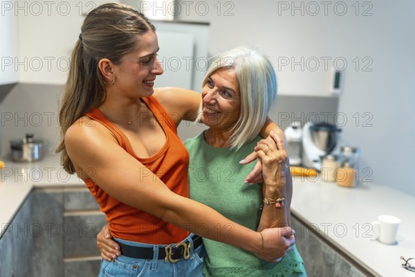 Senior mother and adult daughter hugging, sharing a tender moment of affection and familial bonding in a modern kitchen