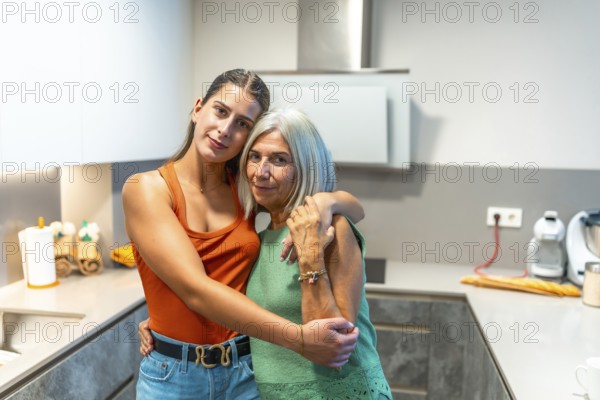 Young woman and senior woman hugging in contemporary kitchen, expressing affection and familial bond