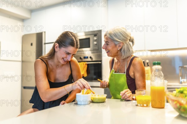 Elderly woman and young woman sharing a joyful moment in a modern kitchen, preparing food and bonding over a meal