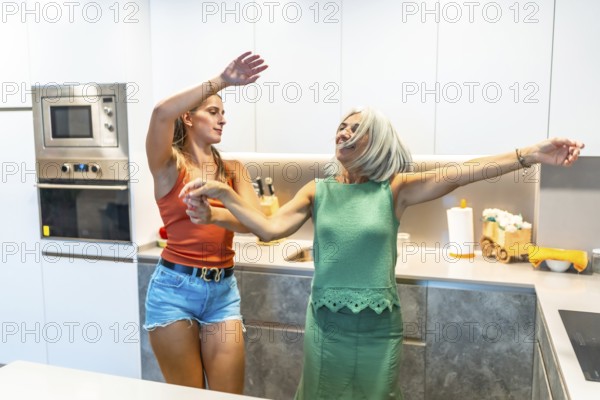 Two women enjoying a lively dance in a sleek, modern kitchen, expressing happiness and energy in a bright, contemporary home setting
