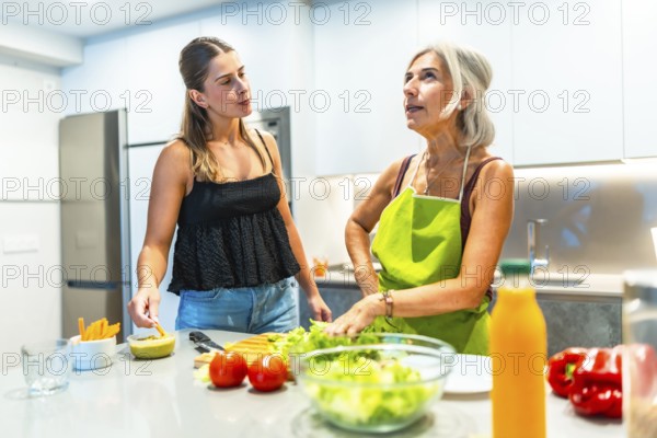 Two women engaging in meal preparation in a modern kitchen, focusing on fresh vegetables and healthy eating habits, fostering family bonding