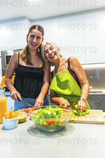 Two women happily preparing a fresh salad in a brightly lit kitchen, showcasing the joy of cooking and healthy living together