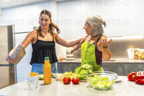 Joyful grandmother and granddaughter preparing a healthy meal in a bright, modern kitchen, surrounded by fresh vegetables and juice