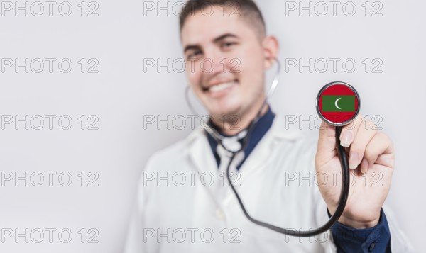 Doctor showing stethoscope with Maldives flag. Maldives national healthcare concept