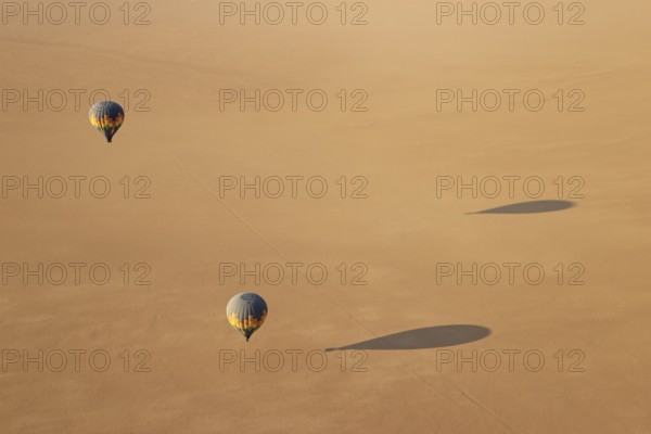 Two hot-air balloons above an arid plain at the edge of the Namib Desert. Aerial view from another balloon. Namibia