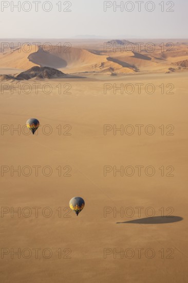 Two hot-air balloons above an arid plain at the edge of the Namib Desert. Aerial view from another balloon. Namibia