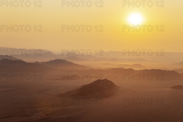 Arid plains and isolated mountain ridges at the edge of the Namib Desert. At sunrise. Aerial view from a hot-air balloon. Kulala Wilderness Reserve, Namibia