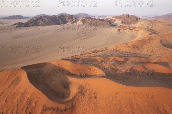Sand dunes and mountain ridges in the Namib Desert. In the evening. Aerial view. Namib-Naukluft Park, Namibia