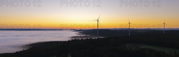 Row of wind turbines along the horizon at sunrise with fog in the distance, near Schorndorf, Remstal, Rems-Murr-Kreis, Baden-Württemberg, Germany