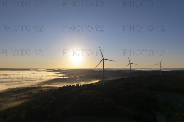 Wind turbines rise into the sky above a misty forest at sunrise, near Schorndorf, Rems-Murr-Kreis, Rems-Murr-Kreis, Baden-Württemberg, Germany