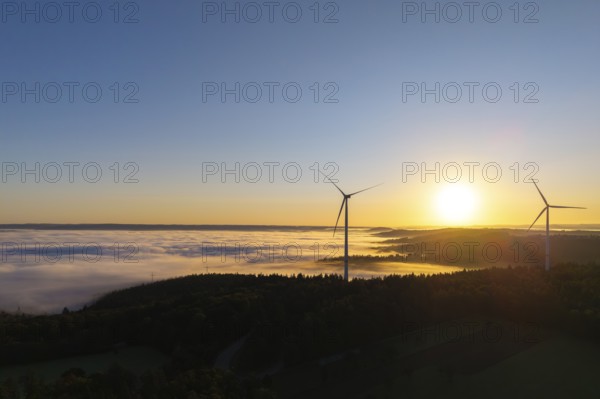 Two wind turbines rise above a fog-covered landscape in the morning light, near Schorndorf, Rems-Murr district, Rems-Murr-Kreis, Baden-Württemberg, Germany