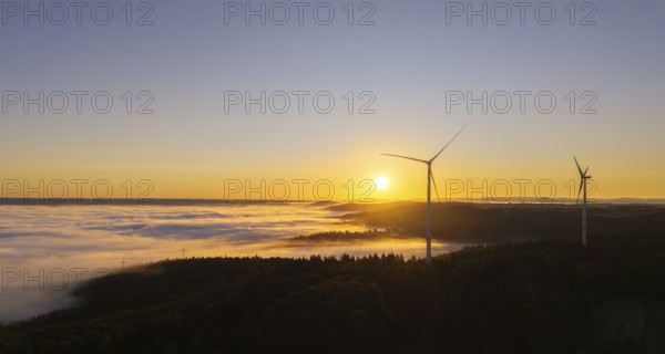 Wind turbines stand in the morning mist under a clear sunrise sky, near Schorndorf, Rems-Murr district, Rems-Murr-Kreis, Baden-Württemberg, Germany