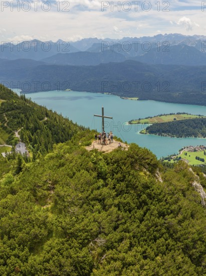 Group on a mountain with summit cross, overlooking a wide lake landscape, Herzogstand summit, Walchensee, Schlehdorf, Germany
